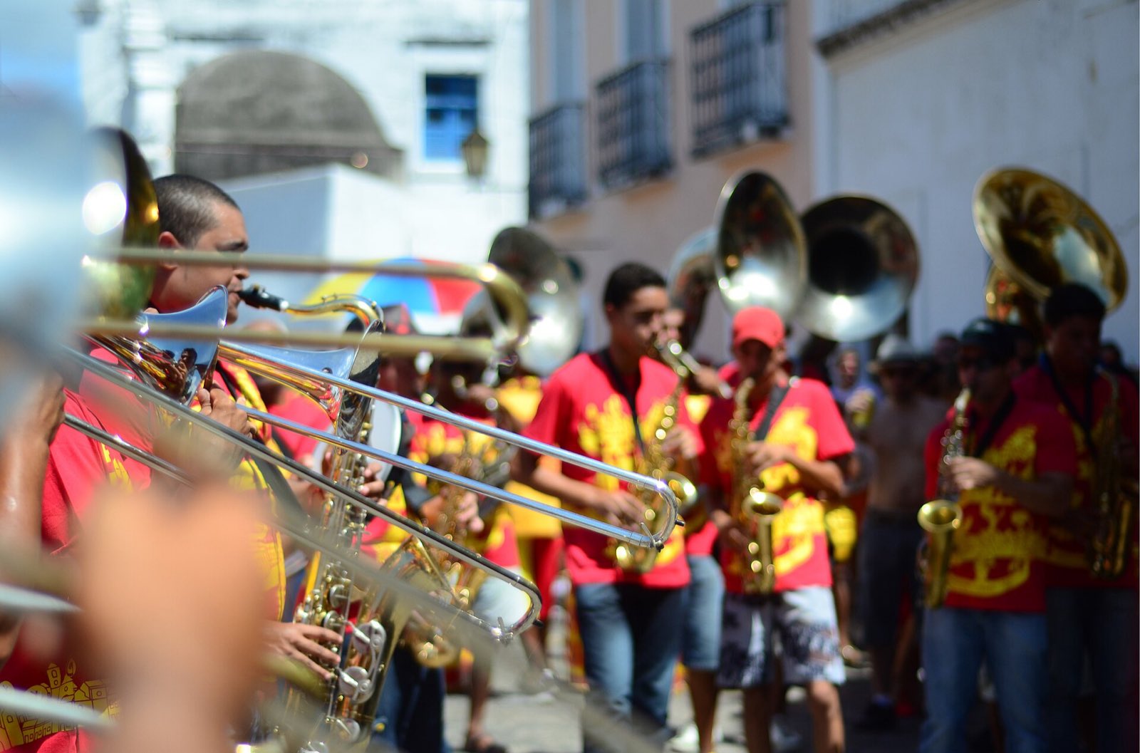 Naipe de metais tocando na rua em Olinda: trombones de vara em primeiro plano, saxofones e um sousafone atrás.